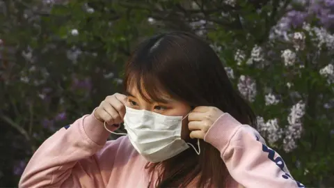 Getty Images Woman putting face mask