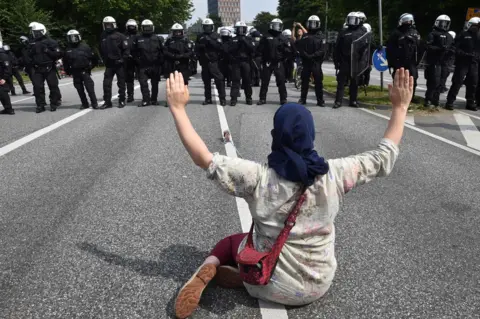 AFP A demonstrator holds her hands up as she faces policemen during a protest on July 7, 2017 in Hamburg, northern Germany, where leaders of the world's top economies gather for a G20 summit
