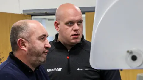 Winmau Lee Huxtable looks at a computer screen with former World Champion, Michael Van Gerwen, to design his darts
