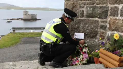 PA Police officer lays floral tribute from Manchester at the church on Barra