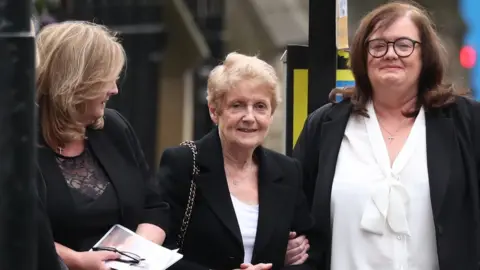 PA Media Anne Donnelly (centre), Declan Donnelly and Fr Dermott Donnelly's mother