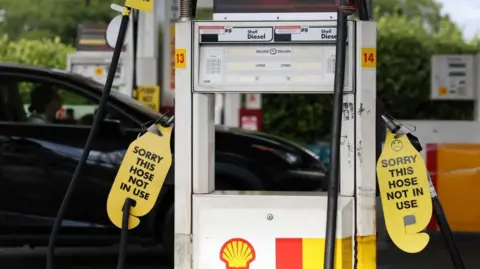 Signs displayed on empty fuel dispensers at a Shell petrol station say 'Sorry this hose is not in use' in Sydney, Australia