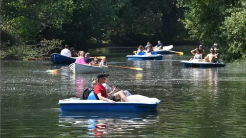 PA People enjoy hot weather on the boating lake in Victoria Park, London