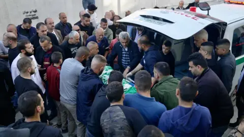 Dave Bull Palestinian mourners gather round the body of Basel Abu al-Wafa, 14, after he was killed during an Israeli military raid in Jenin, in the occupied West Bank (29 November 2023)