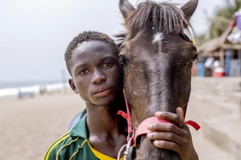 Grace Ekpu/BBC Man and horse looking at camera