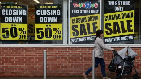 Getty Images A customer walks past a Toys 'R' Us store with 'closing down sale' signs in the windows in south London on February 9, 2018