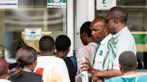 Getty Images People getting their hands sanitised as they enter a bank