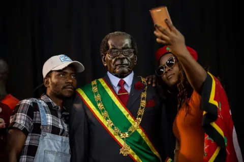 AFP Attendees at the South African political party, the Economic Freedom Fighters (EFF) hosted memorial service held in honour of late Zimbabwean President Robert Mugabe take pictures with a wax model of the Former President in Soweto, Johannesburg on September 12, 2019.