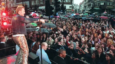 Getty Images Pop singer Ronan Keating performs his UK single "Life is a Rollercoaster" in front of 2000 drenched fans outside the new HMV store in Oxford Street on May 21, 2000