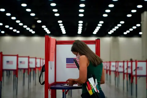 A woman completes her ballot in a voting booth A woman completes her ballot in a voting booth
