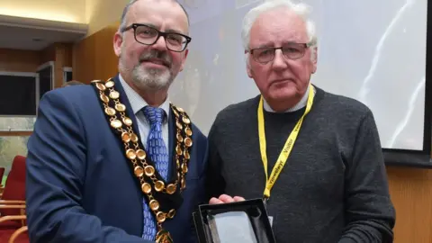 Noel Thomas with the council leader, receiving his honour