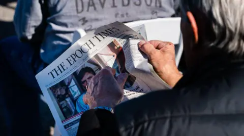 An attendee reads a copy of The Epoch Times newspaper during a Defend The Majority Event in Augusta, Georgia, U.S., on Thursday, Dec. 10, 2020