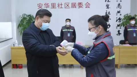 EPA Chinese president Xi Jinping has his temperature recorded during a trip to a hospital in Beijing