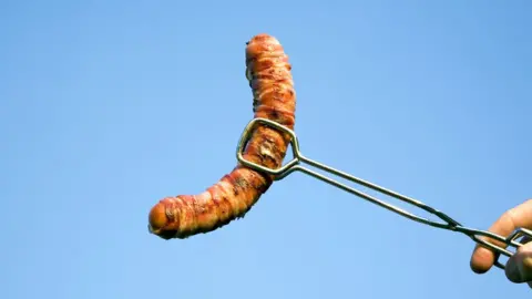 Getty/Gaby Wojciech cooked sausage on BBQ tong