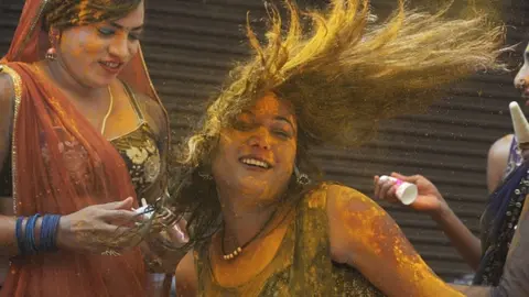 Getty Images Revellers smeared in coloured powder dance during the Holi celebrations, the Hindu spring festival of colours, in Hyderabad on March 17, 2022.