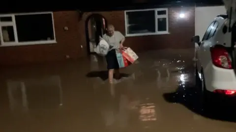 Woman carrying bags from her home in flooding