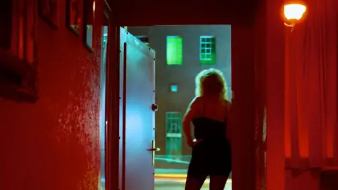 Getty Images A woman stands at the door of a hotel room