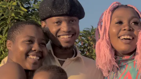 Three people holding a baby