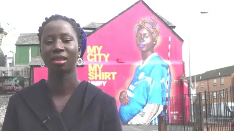 Maimuna Indjai with her mural after it was vandalised