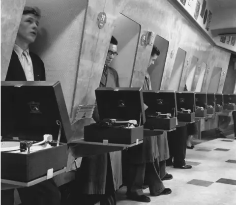 Getty Images Customers listen to the latest record releases at a listening booth in the HMV shop at 363 Oxford Street, London, 24th November 1955