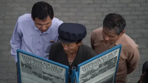 Getty Images North Korean men read a newspaper in the street in Pyongyang (file image)