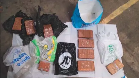 Essex Police Blocks of cocaine and heroin laid out on the ground, surrounded by bags, after they were seized from Charlie Lancaster's car by police