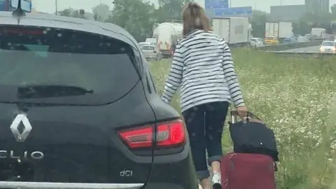 Liam Chapman woman walks along road with luggage