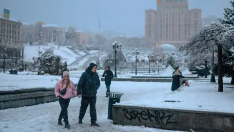 Getty Images People walk through a snowy scene in Kyiv