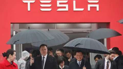 Getty Images Mr Musk walks with Shanghai Mayor Ying Yong in the rain