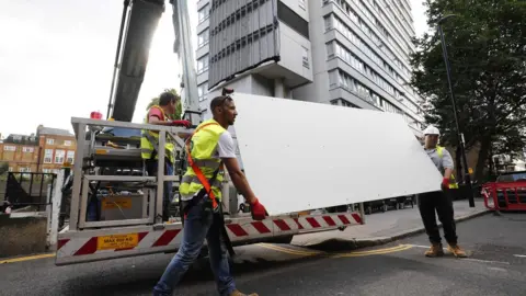 AFP/Getty Images Workers removing cladding from a London tower block