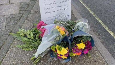 PA Media Flowers left at entrance to Bibby Stockholm