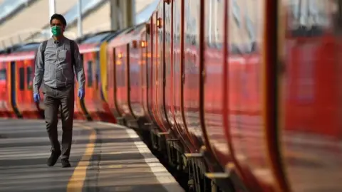 AFP A man walks by trains wearing a mask