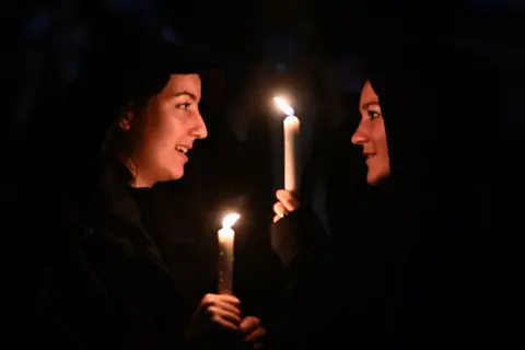 Ben Stansall/Getty Images People hold candles outside Buckingham Palace