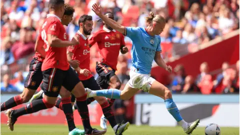Manchester United players Aaron Wan-Bissaka, Bruno Fernandes, Raphael Varane and Casemiro chase Erling Haaland of Manchester City