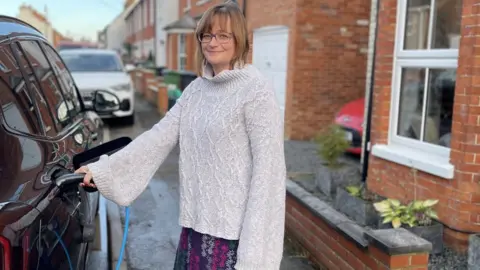 Kerbo Charge woman holding charger plugged into car