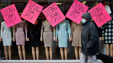 Getty Images Person walking past shop which is closing down