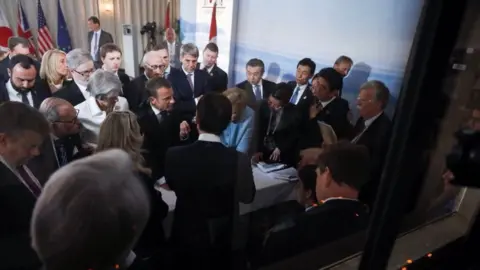 French presidency G7 leaders gather in a tight crowd around a narrow table