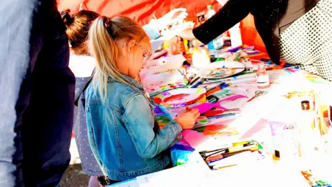 Curious Arts Child colouring in at a mini pride event