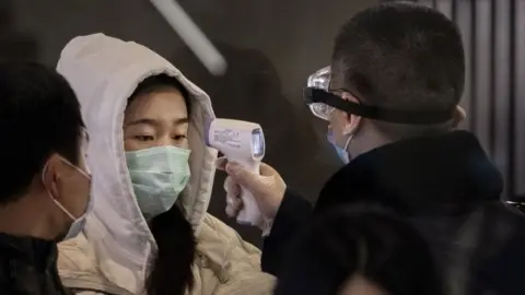 Getty Images Train passenger being checked for fever