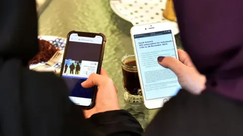 AFP File photo shows women looking at the internet on their mobile phones in Saudi Arabia (27 November 2019)