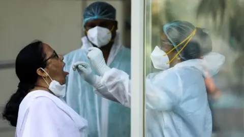 Reuters A healthcare worker in personal protective equipment (PPE) collects a swab sample from a woman during a testing campaign for the coronavirus disease (COVID-19), in Navi Mumbai, India