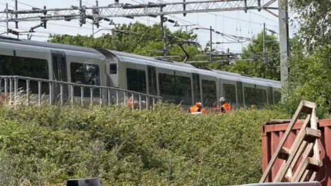 People in high vis can be seen inspecting a train. It's taken from distance so the details aren't very clear