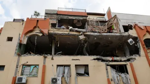 Reuters A building damaged in an Israeli air strike in the Gaza Strip (9 May 2023)