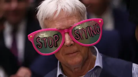 Getty Images a protester in a pair of oversized glasses emblazoned with the words "stop spying"