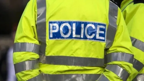 A stock image of a neon yellow police vest with the word police written on the back in white letters on blue background.