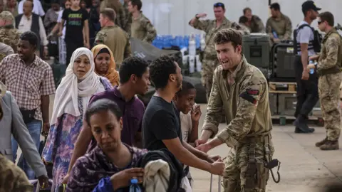 PA Media British military personnel help Britain nationals board flights at Wadi Seidna Air Base in Khartoum, Sudan