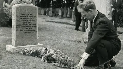 Postman Ian Robertson at the grave of the Unknown Bairn in 1971