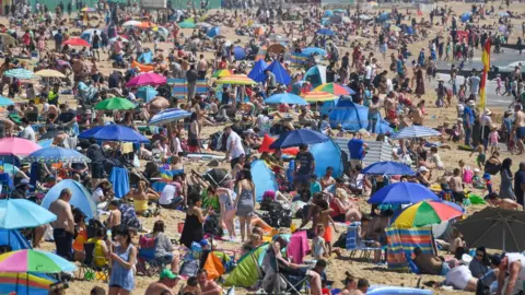 Getty Images Crowds enjoy the sunshine on Bournemouth beach in Dorset on Bank Holiday Monday