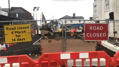 John Devine/BBC Excavation work taking place in March town centre, with a road closed off by workmen