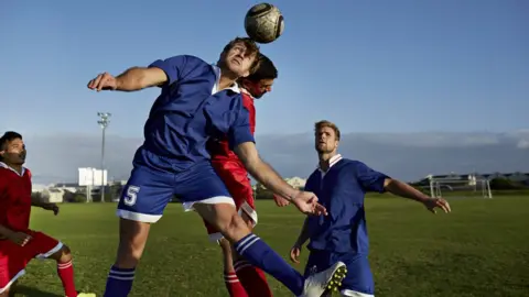 Getty Images Male footballers going up to head a ball